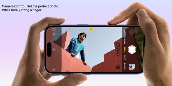 Hands hold a smartphone horizontally to photograph a person on a rooftop; on-screen camera controls and a live indicator are visible against a soft purple gradient background.