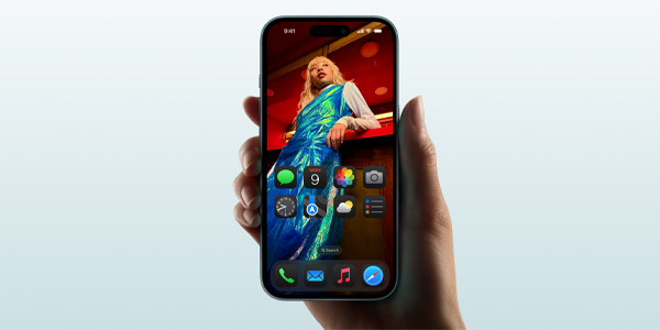 Hand holding a smartphone showing a home screen with a large photo of a person wearing a blue dress as wallpaper.