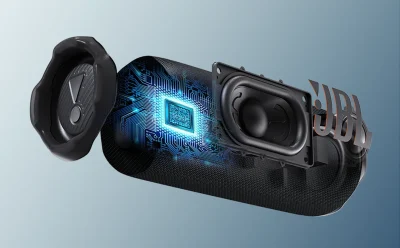 Exploded view of a portable speaker showing the driver, circuitry, and a glowing microchip with USB branding on the shell.