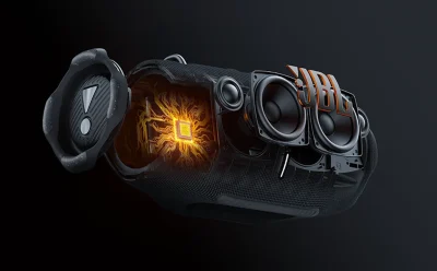 Exploded view of a JBL portable speaker showing internal circuitry and glowing core components with an orange JBL logo nearby.