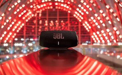 JBL portable speaker on a glossy red surface with a red-illuminated tunnel in the background.