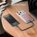 Two smartphones plugged into a multi-output charger on a wooden table, illustrating simultaneous charging.
